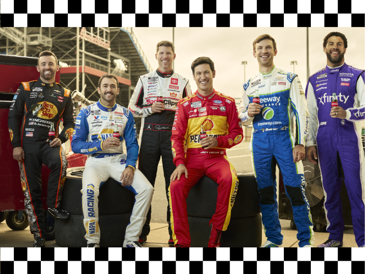NASCAR drivers posing at the speedway with Coca‑Cola bottles framed by black and white checkered border, promoting VIP NASCAR 500 race day access.