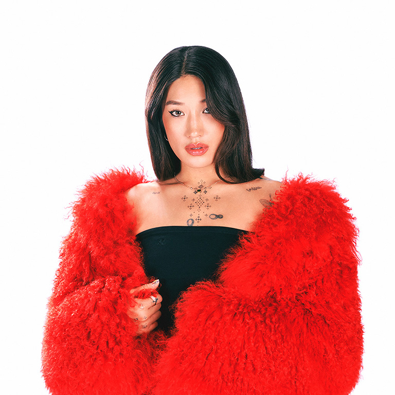 Peggy Gou, con una chaqueta de piel roja, sobre un fondo blanco.