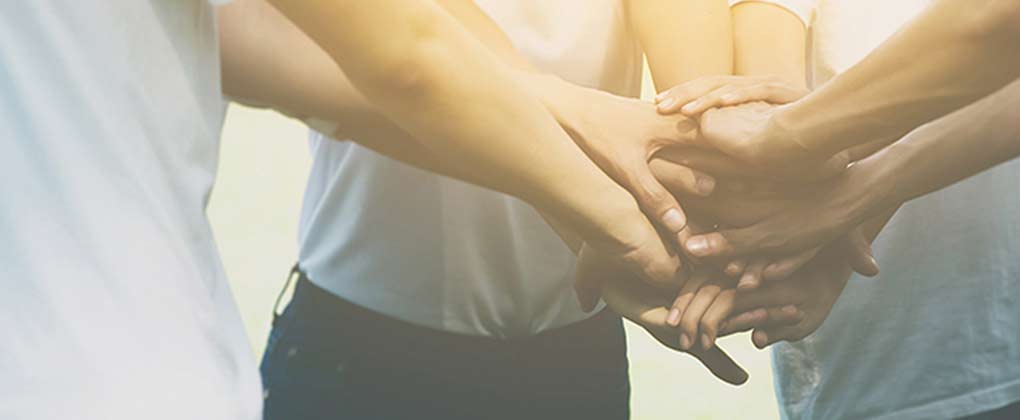 Different people holding their hands together in a circle