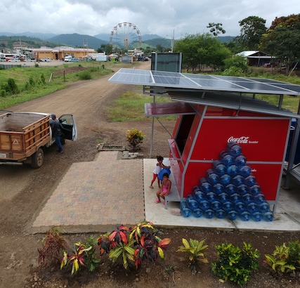 Coca-Cola stand in a local community with a ferris wheel & buildings in the background